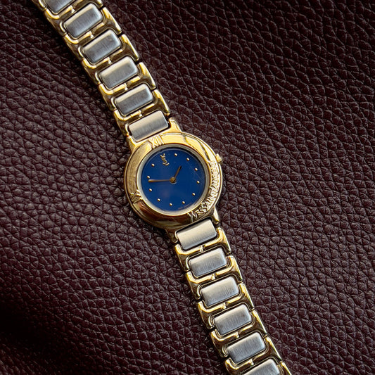 YSL Gold and silver watch with blue face on a brown textured background