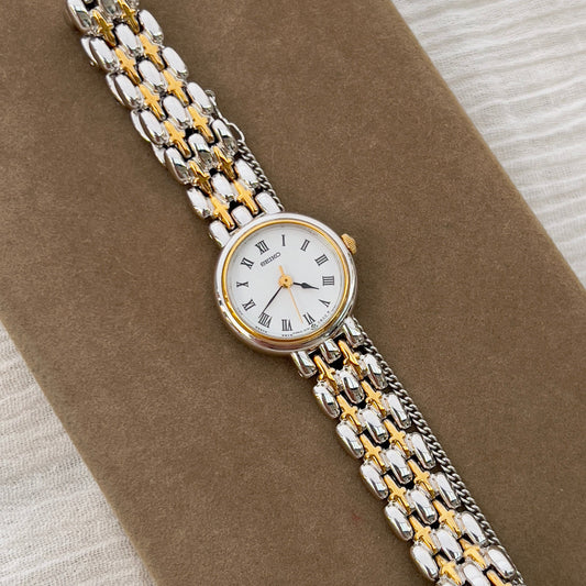 Seiko vintage ladies dress watch with two-tone gold and silver bracelet, white Roman numeral dial, and spade hands – classic quartz timepiece from Gilded Hour NZ.