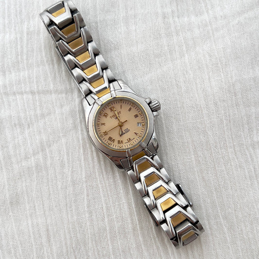Two-tone watch with silver and gold band on a white fabric background