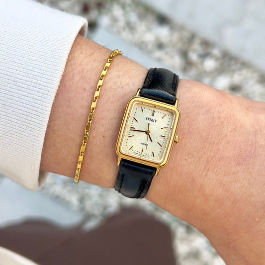 Elegant vintage Seiko gold-tone ladies watch with square case and brown leather strap, worn outdoors on wrist with gold bracelet.