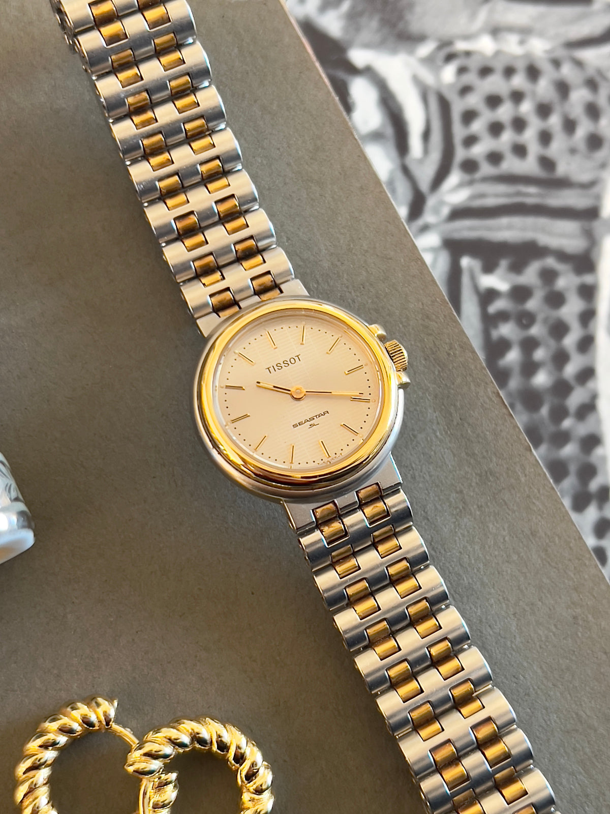 Tissot Seastar Two-tone watch with gold and silver band on a textured surface