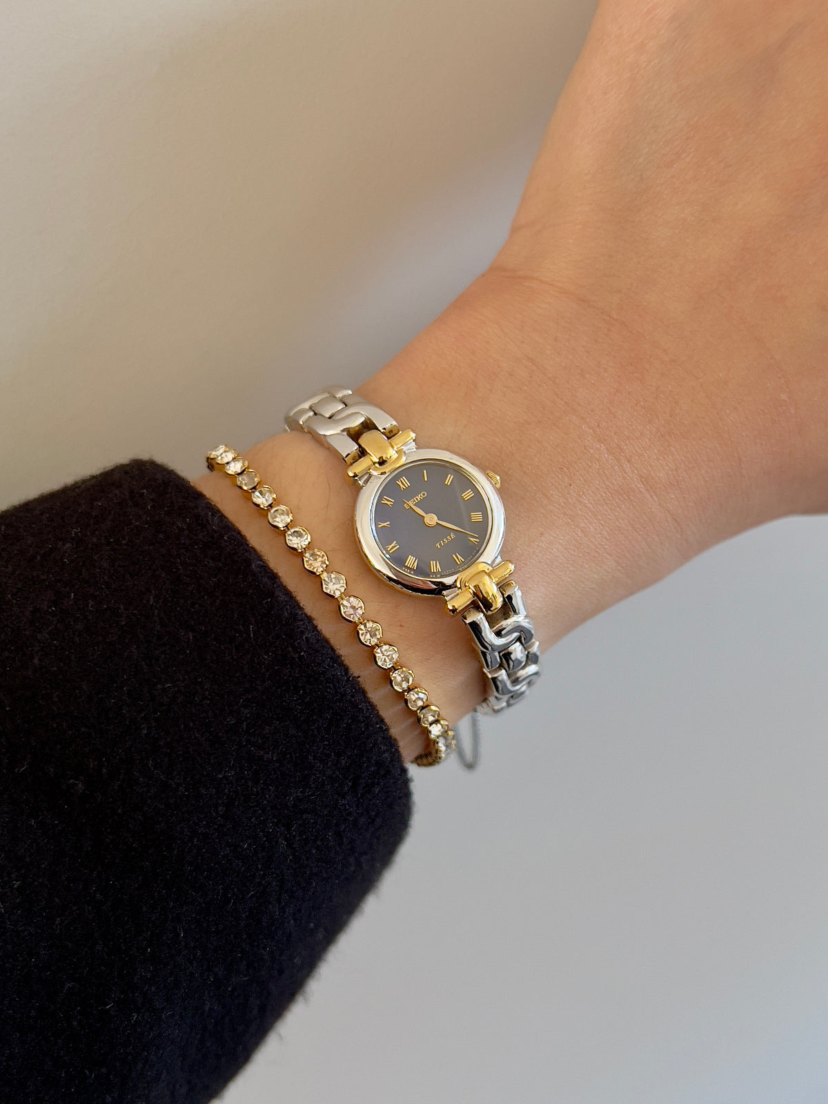 Woman's gold and silver Seiko watch on a wrist with a neutral background