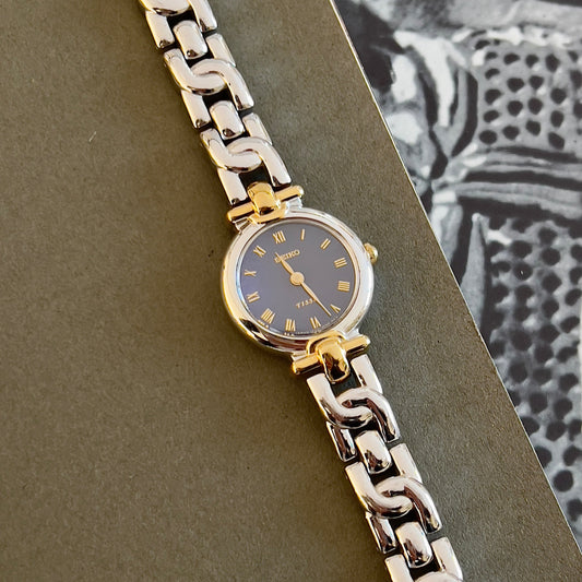 Seiko Tisse silver and gold watch with a blue face on a textured surface