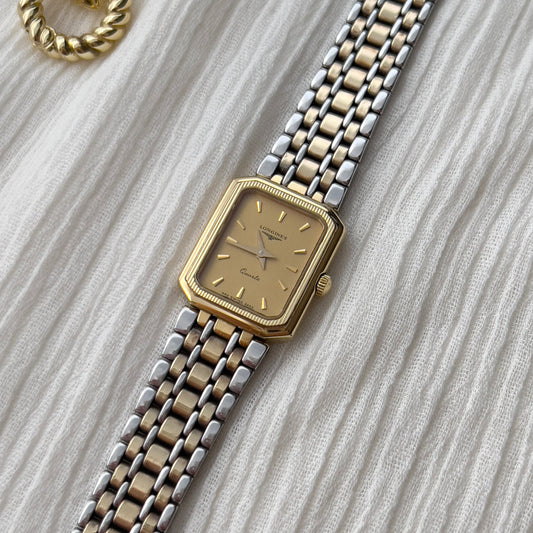 longines gold and silver woman's watch on a textured surface