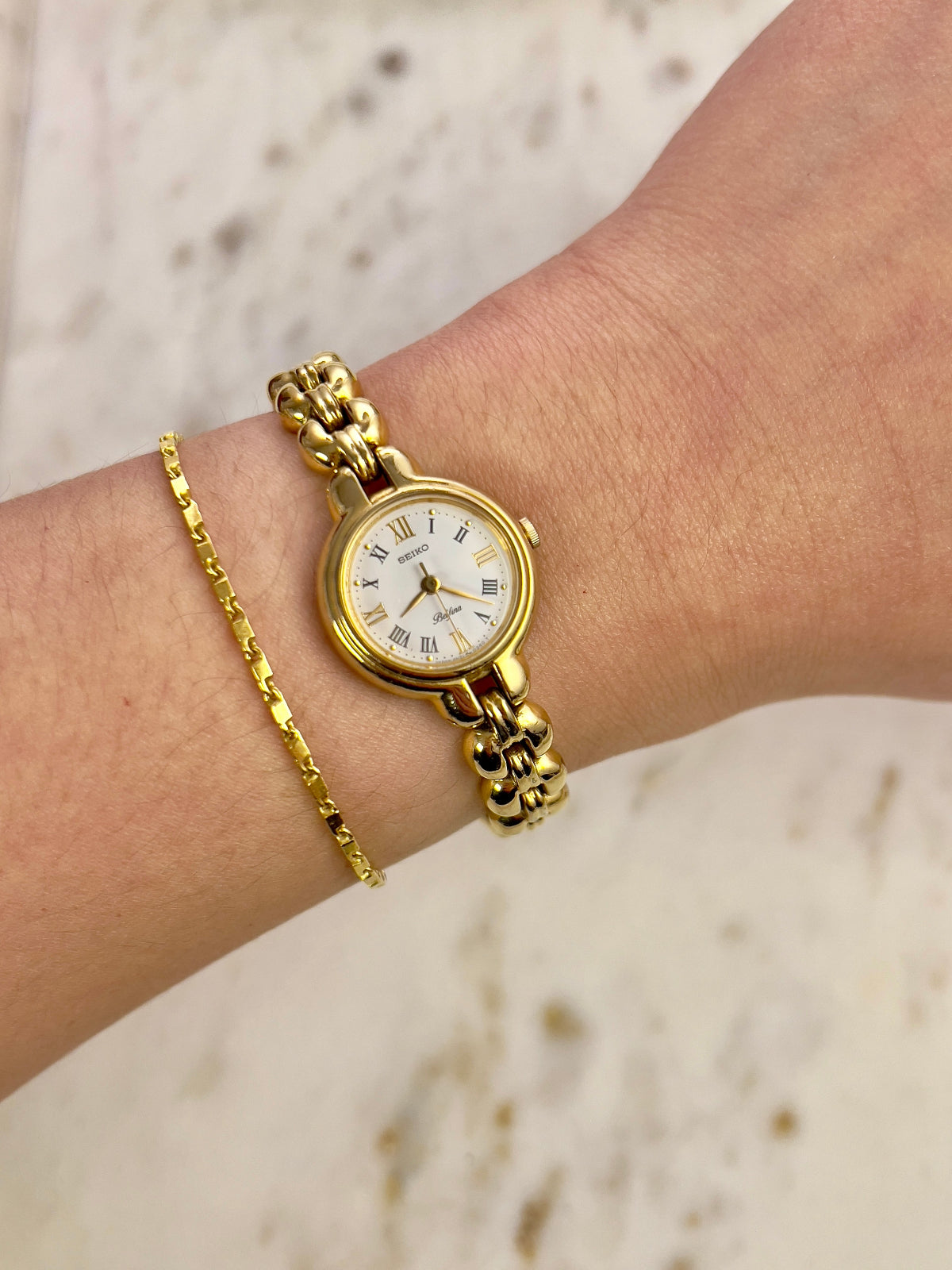 Seiko gold watch and bracelet on a wrist with a blurred background