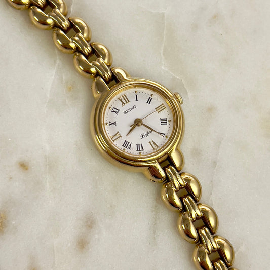 Gold watch with a white face on a marble surface