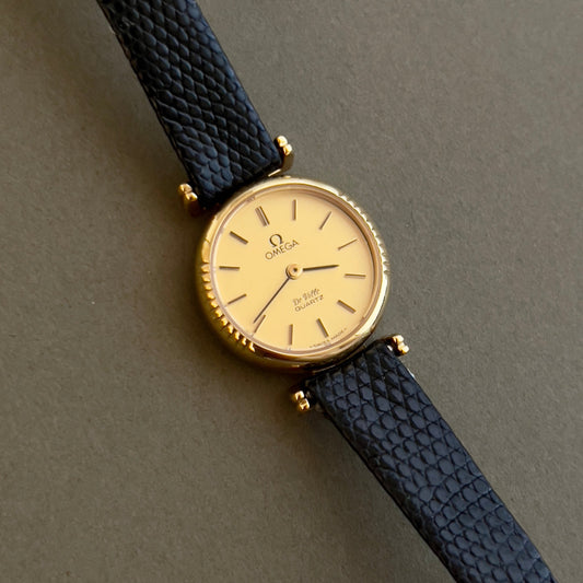 Omega old watch with a lizard skin strap on a gray background