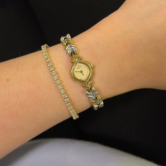 Seiko gold watch and bracelet on a wrist against a black background