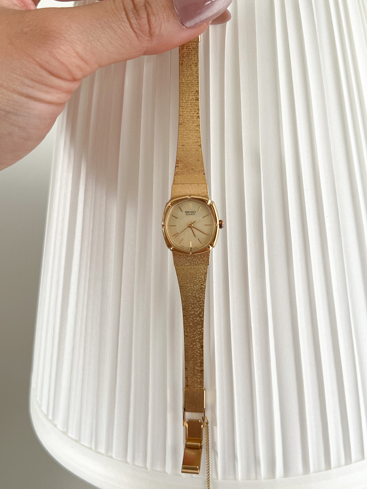 Seiko Gold Cushion Tatami Bracelet Women’s Watch — Held full watch in front of a pale curtain