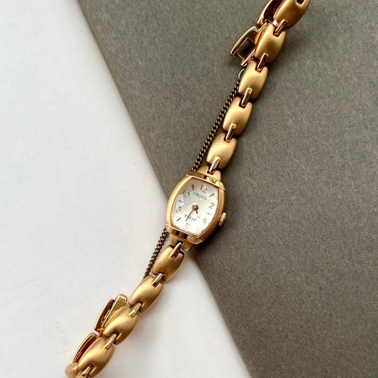 Seiko Tisse ladies gold bracelet watch with domed crystal and matte finish on neutral background