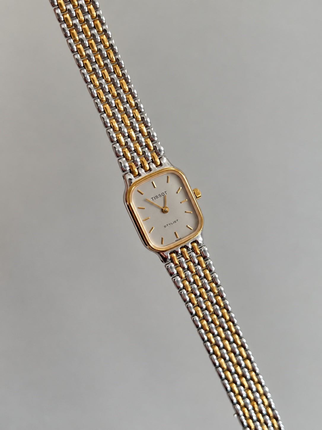 Tissot Stylist rectangular silver dial watch displayed with the two tone bracelet extended.