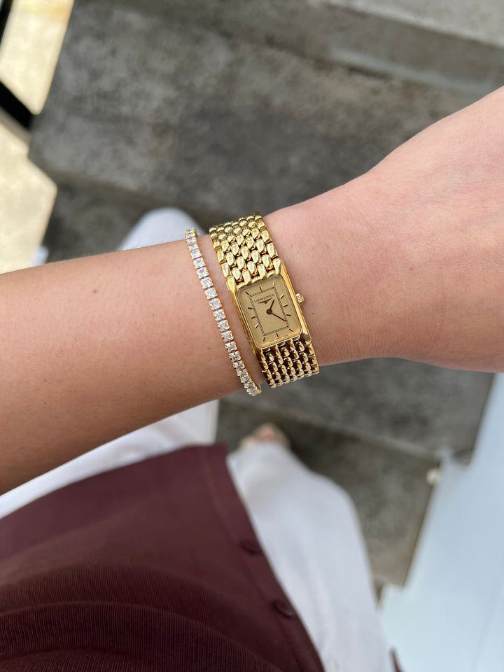 Gold rectangular Longines jewellery watch worn with a crystal bracelet