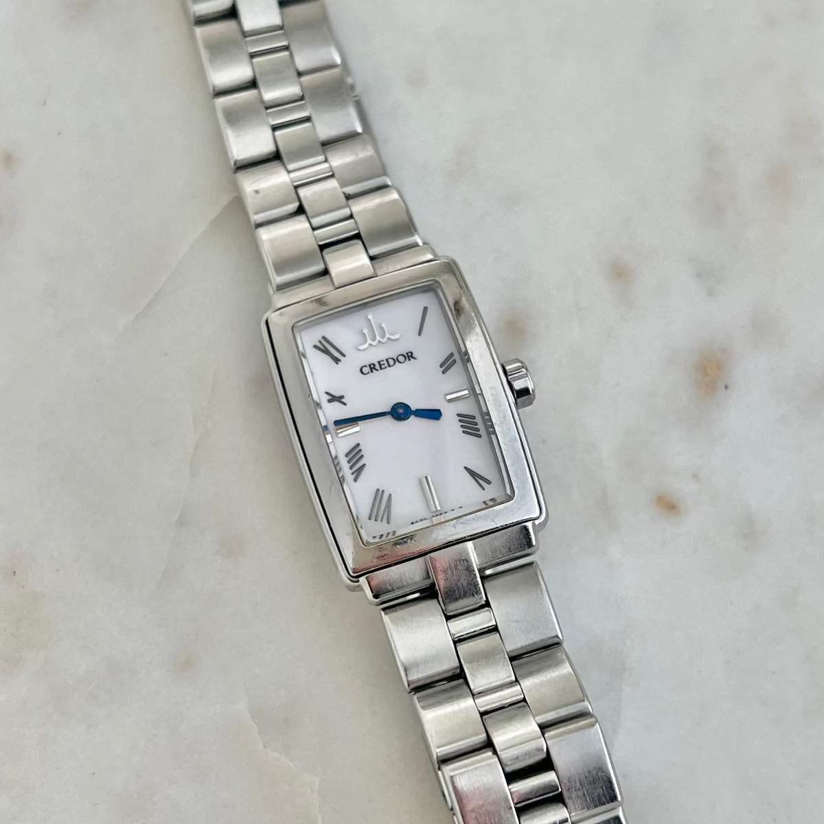 Silver Credor Ladies' watch with a white face on a marble surface