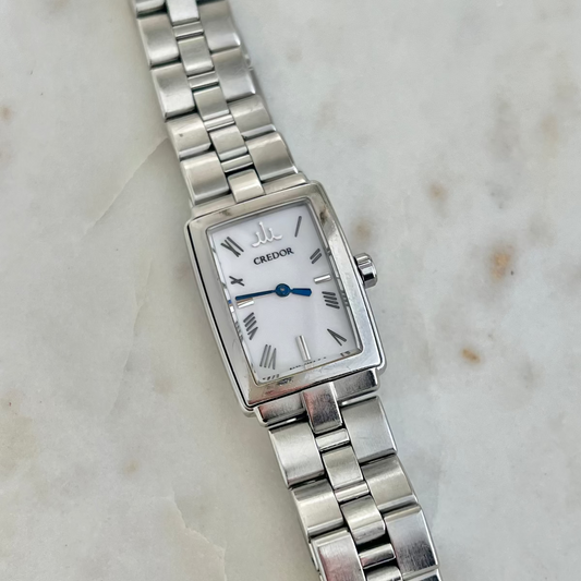 Silver Credor Ladies' watch with a white face on a marble surface