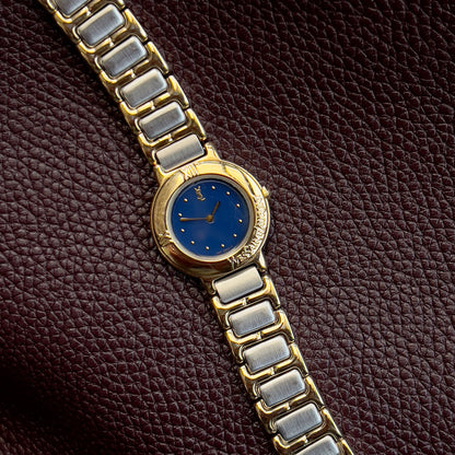 YSL Gold and silver watch with blue face on a brown textured background