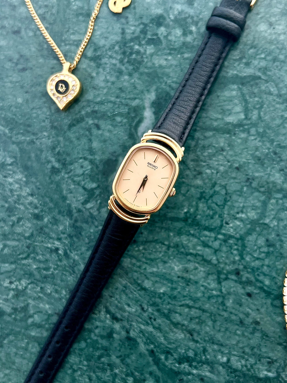 Seiko Vintage Women's Watch style watch with black strap and gold case on a textured green surface | The Gilded Hour NZ Australia Collection