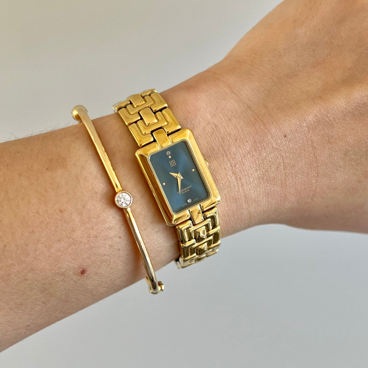 Givenchy Gold Women's watch and bracelet on a wrist against a neutral background