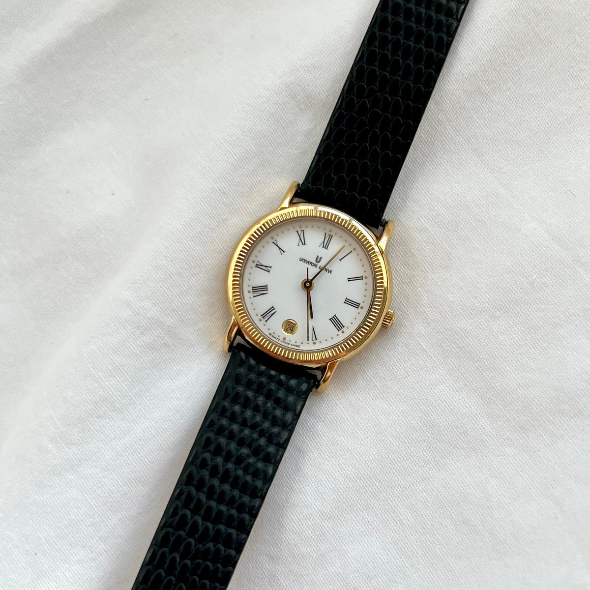 Gold Universal Geneve Women's Watch with black strap and gold case on a white background