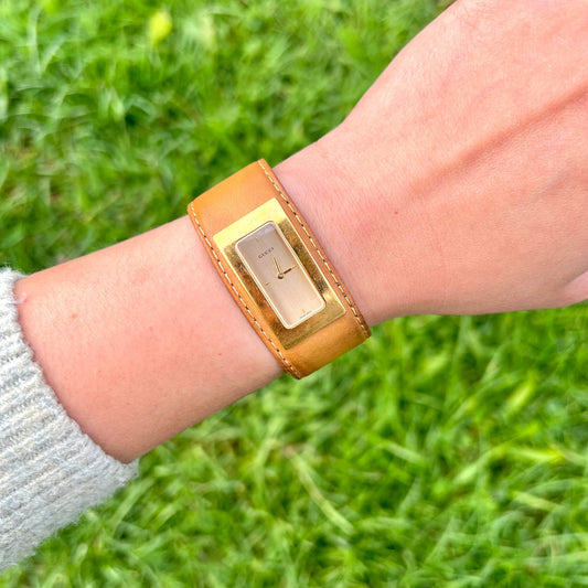 Gucci Gold Cuff Watch 7800S on a wrist against a grass background