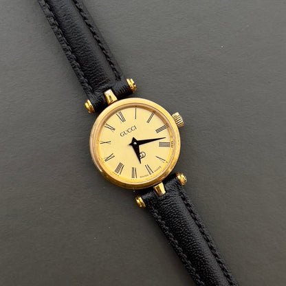 Gucci Sherry woman's watch with black leather strap on a dark gray background