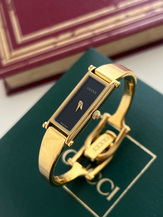 Gold Luxurious watch nz on a green surface with blurred background