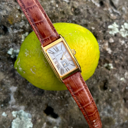 Hamilton Ardmore Gold Watch with brown leather strap on a stone surface with a lemon
