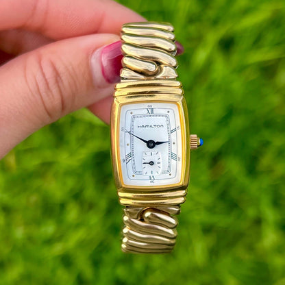 Hamilton Benton Gold Women's Watch held by a hand against a grassy background