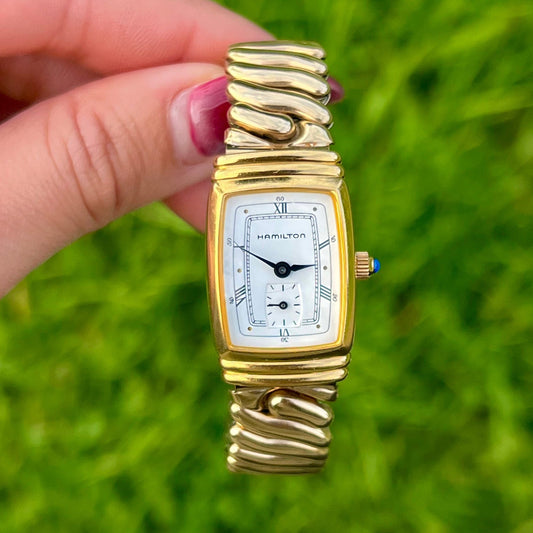 Hamilton Benton Gold Women's Watch held by a hand against a grassy background