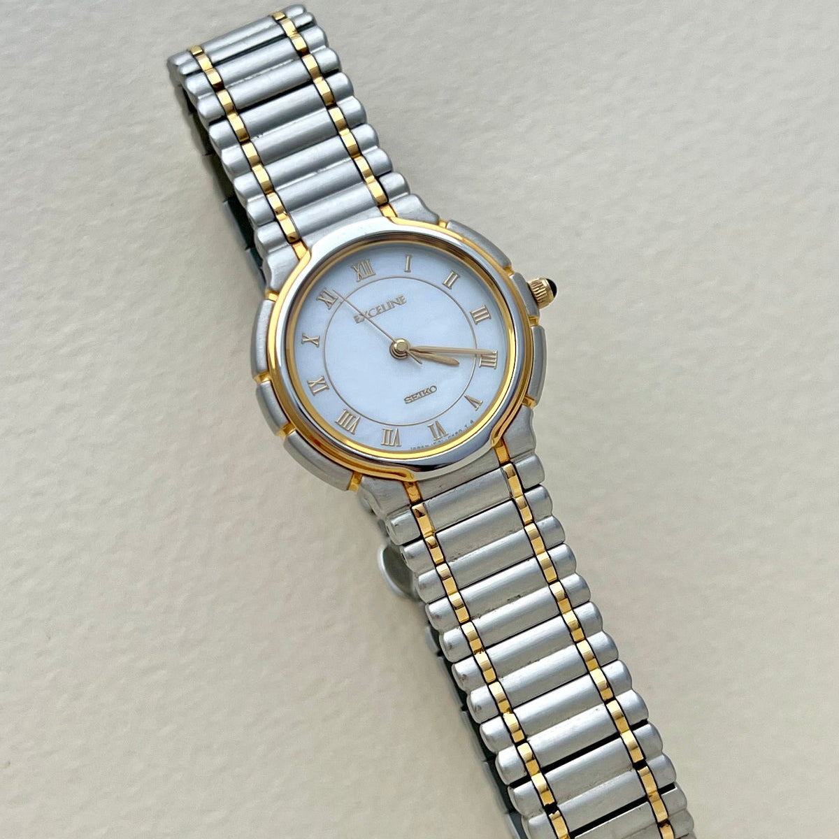Two-tone Seiko Women's Exceline watch with silver and gold band on a light gray background