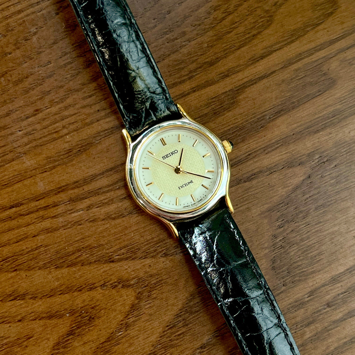 Vintage Seiko women's watch with black leather strap on a wooden surface