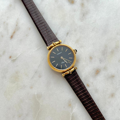 Tissot Watch with a brown strap and gold case on a marble surface
