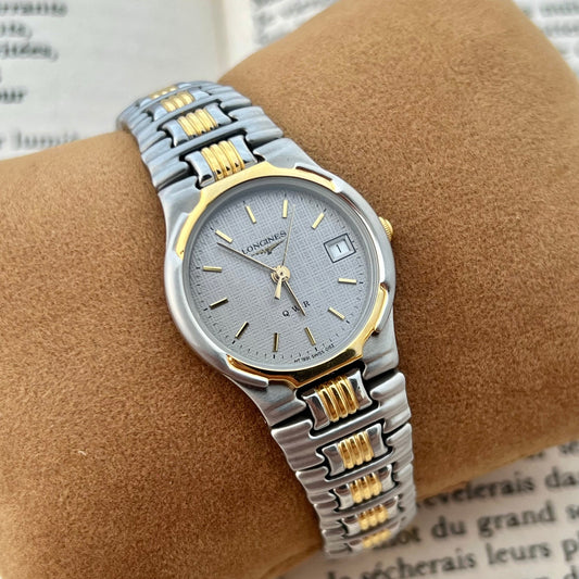 Two-tone Longines Women's watch with silver and gold band on a brown cushion with text background
