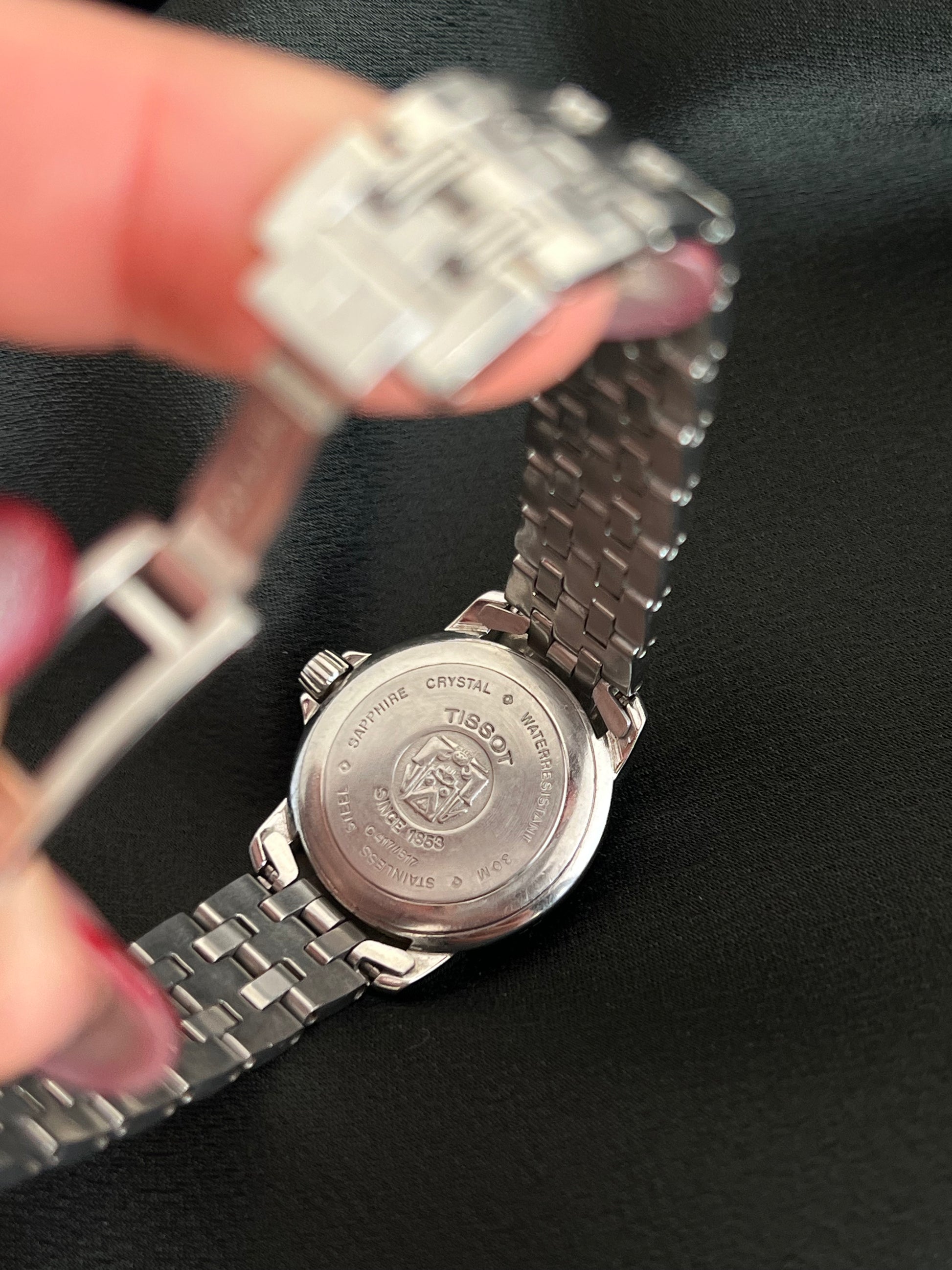 Silver watch with Tissot logo on a black background