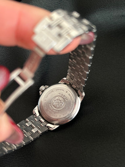 Silver watch with Tissot logo on a black background
