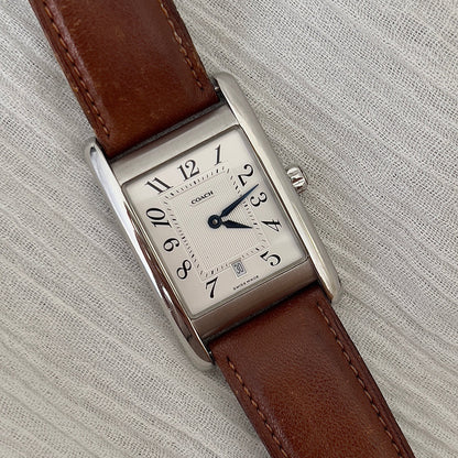 Coach watch with brown leather strap on a light gray background