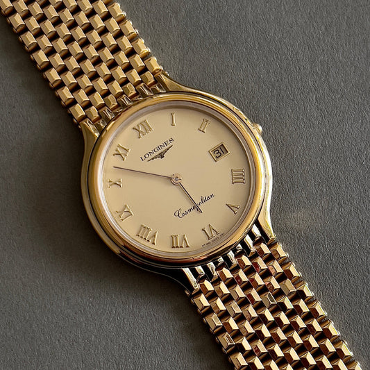 Longines gold wristwatch with a detailed face on a gray background