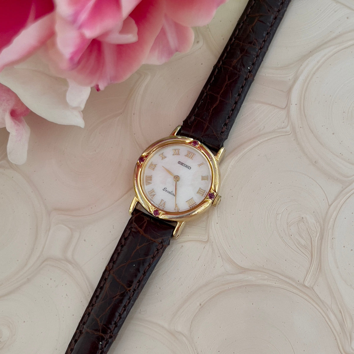 Vintage Seiko Exceline ladies gold quartz watch with petite round case, Roman numeral white dial, ruby cabochon details and brown leather strap – women’s dress watch NZ.