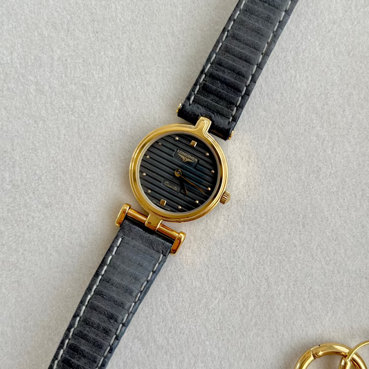 Longines Watch with black strap and gold case on a light gray background