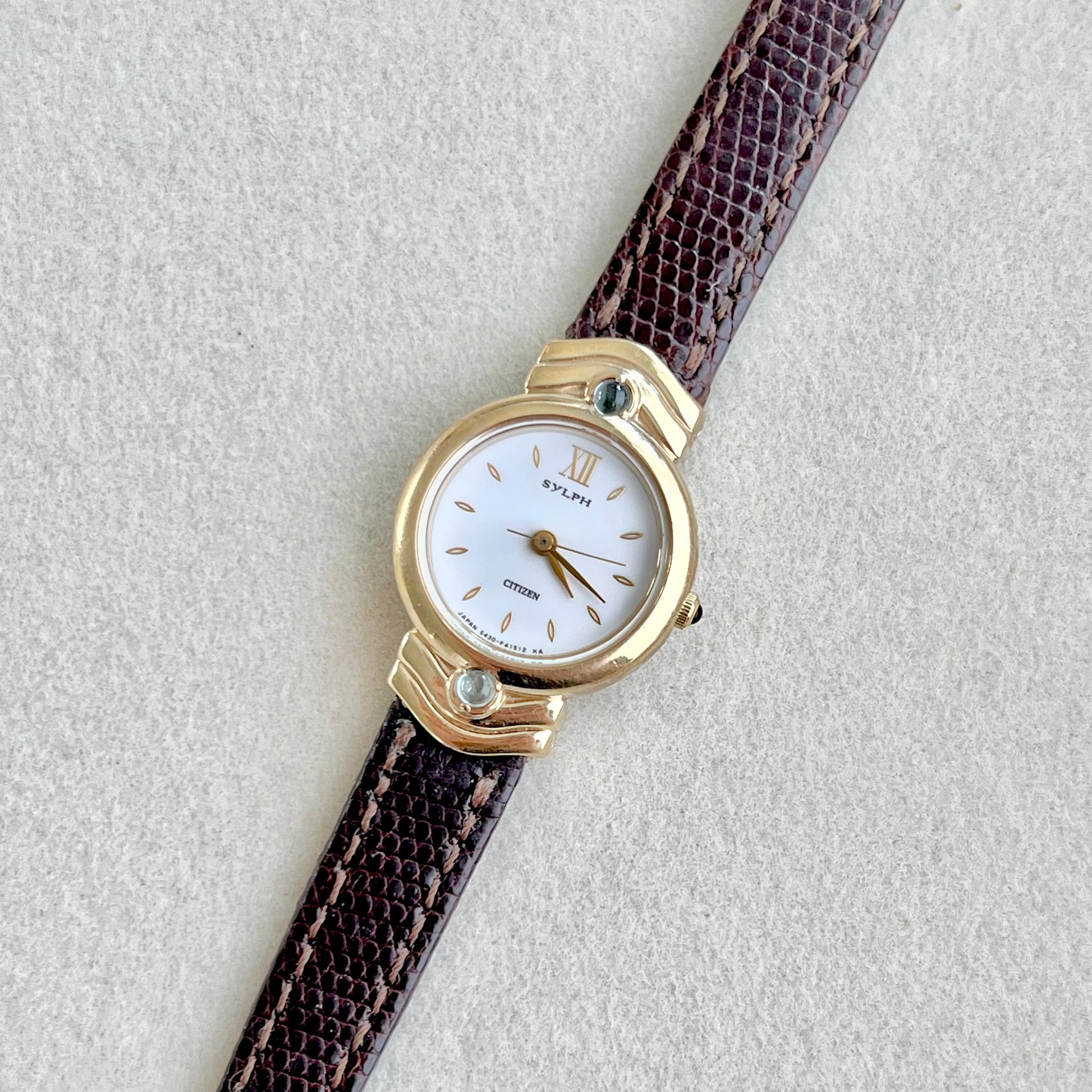 Citizen Sylph Blue Stones with brown strap and gold case on a light gray background