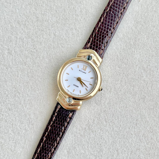 Citizen Sylph Blue Stones with brown strap and gold case on a light gray background