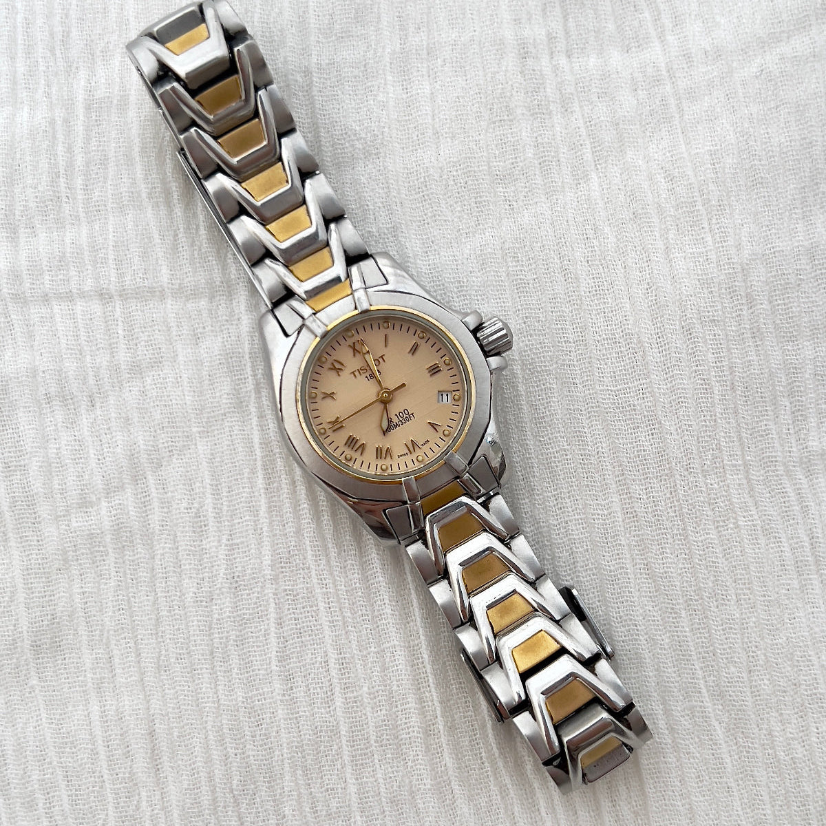 Two-tone watch with silver and gold band on a white fabric background