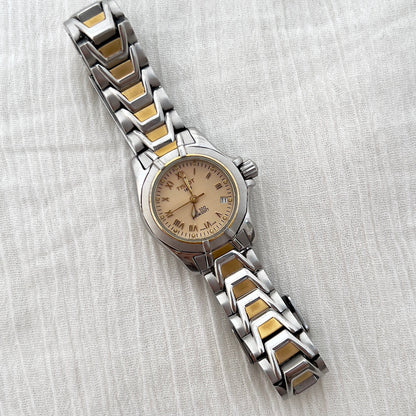 Two-tone watch with silver and gold band on a white fabric background