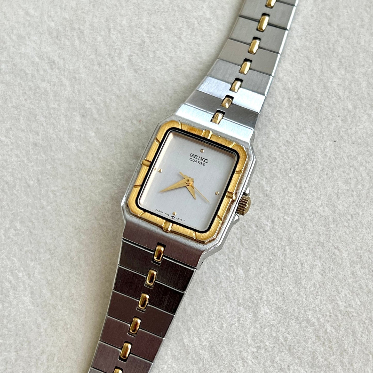 Seiko Woman's Wristwatch Integrated bracelet with silver and gold band on a light gray background