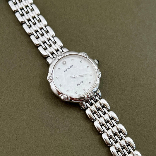 Silver watch with a chain strap on a green background
