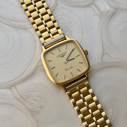 Vintage Longines gold square watch with champagne dial and waffle texture on wrist, paired with crystal bracelet.