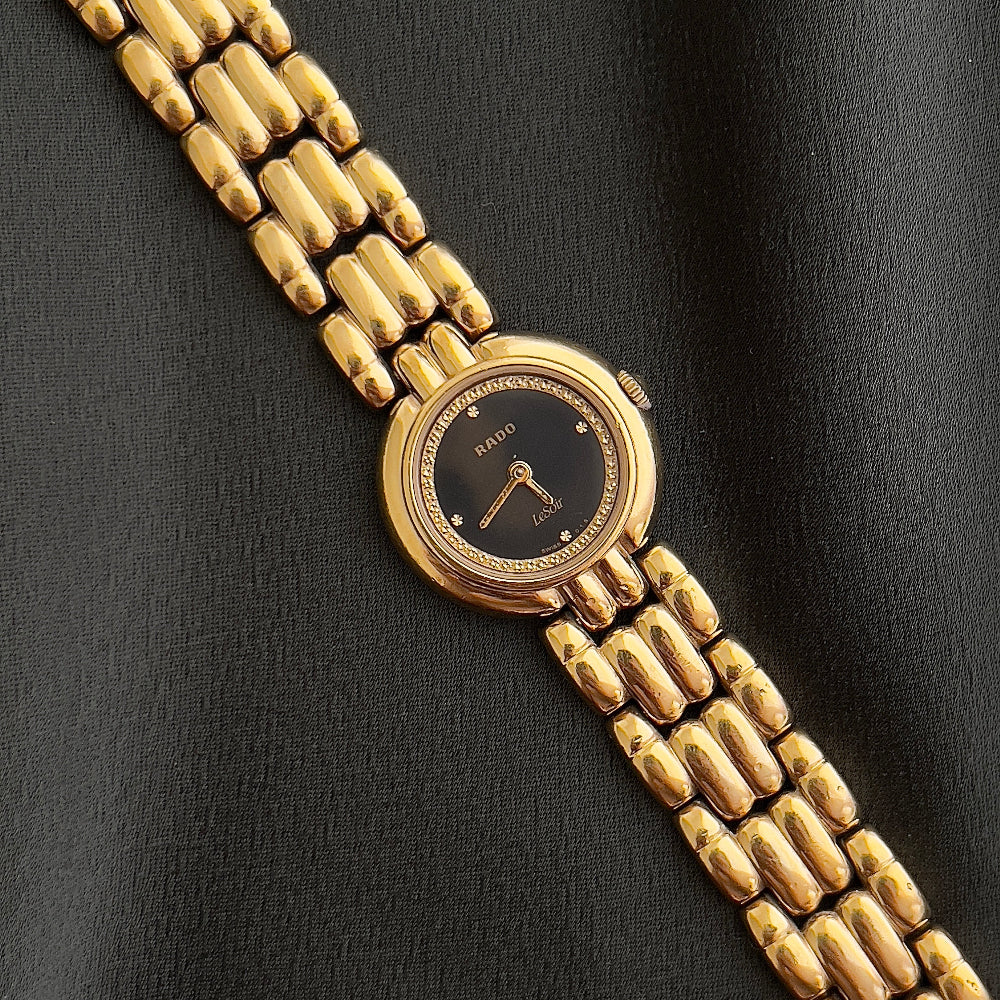 Gold watch with a black face on a black background