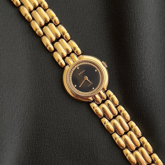 Gold watch with a black face on a black background