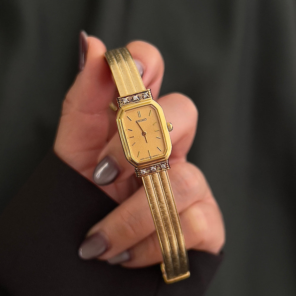 Vintage Seiko gold ladies bracelet watch with champagne dial and crystal accents held in hand