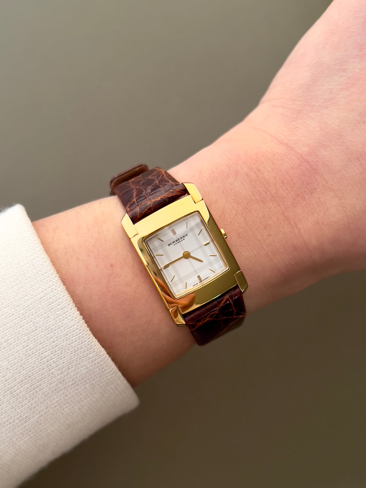 Burberry London rectangular gold ladies watch with white dial and brown croc-embossed leather strap, displayed on neutral background.