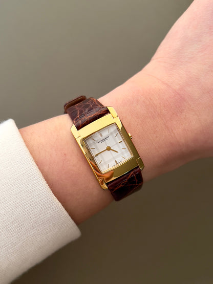 Burberry London rectangular gold ladies watch with white dial and brown croc-embossed leather strap, displayed on neutral background.